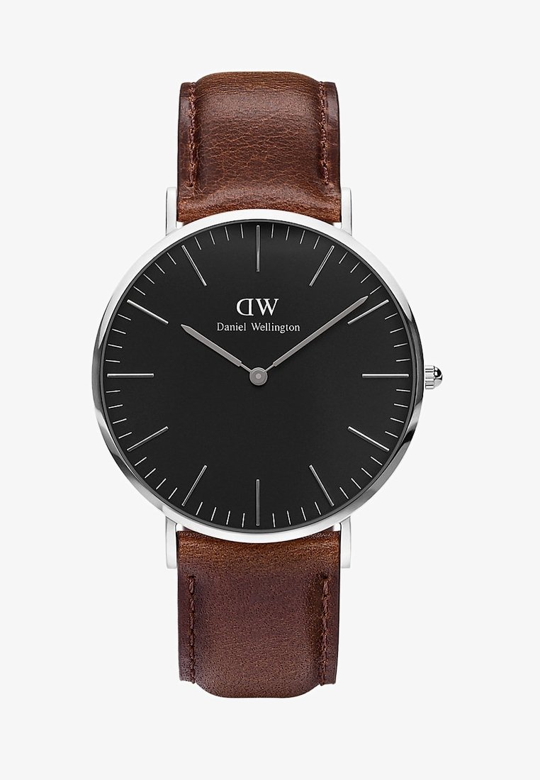 Cadran rond noir de montre Daniel Wellington avec des marqueurs d'heure et des aiguilles argentés, associé à un bracelet en cuir marron. Heure : 10h09.