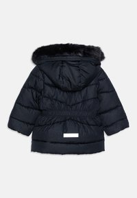 Giubbotto puffy blu navy con cappuccio in pelliccia sintetica, vita arricciata e texture a piuma orizzontale. Presenta una toppa riflettente con logo sulla parte posteriore.