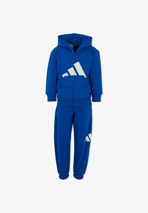 Conjunto de sudadera y pantalones de chándal azul, fabricado en algodón, con un logotipo blanco de Adidas en el frente y en el muslo, y con puños y cinturillas acanaladas.