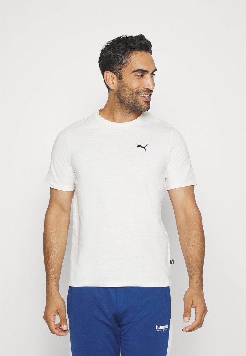 Hvid t-shirt med korte ærmer lavet af bomuld, med et sort Puma-logo på venstre bryst. Rund hals med lige kant og sideetiket.