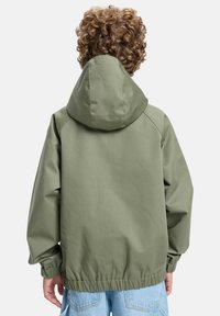 Vihreä, hupullinen takki, jossa on rento istuvuus, joustavat hihansuut ja kiristetty vyötärö. Takissa on sileä, teksturoitu kangas.