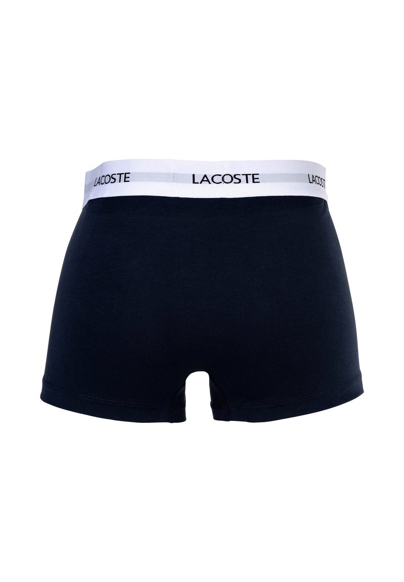Navy cotton boxer shorts with a white waistband featuring the logo "LACOSTE" in black. Smooth texture and fitted design.