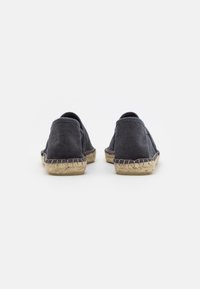 Espadrilles en toile gris foncé avec une finition texturée et des semelles en jute tissé, présentant un design minimaliste et un style à enfiler.