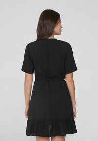 Schwarzes Kleid mit kurzen Ärmeln, subtiler Taillierung und gerafftem Saum. Glattes Material, einfaches Design und knielanger Schnitt.