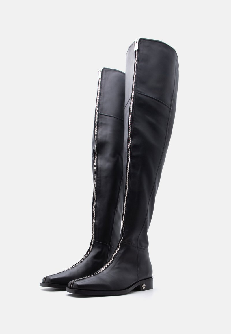 Black knee-high leather boots with front silver zipper detail and low block heel on a white background.