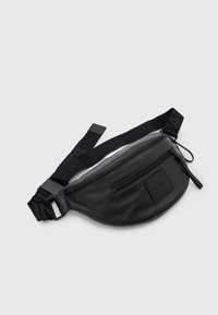 Zwarte leren heuptas met twee ritssluitingen en een verstelbare zwarte stoffen riem met logo-tekst.