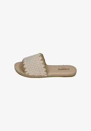 Beige slip-on sandal with a wide crocheted strap, flat sole, and Espadrille-style stitching along the edges.