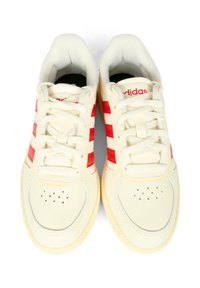 Baskets crème avec trois bandes rouges, bout rond, col rembourré et semelle en caoutchouc texturée. Possède des perforations sur le bout.