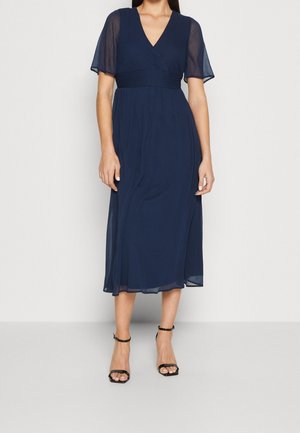 Marineblå, mellemlang kjole med korte, gennemsigtige ærmer, en omslaget V-udskæring og en tætsiddende talje. Glat tekstur med flydende nederdel.