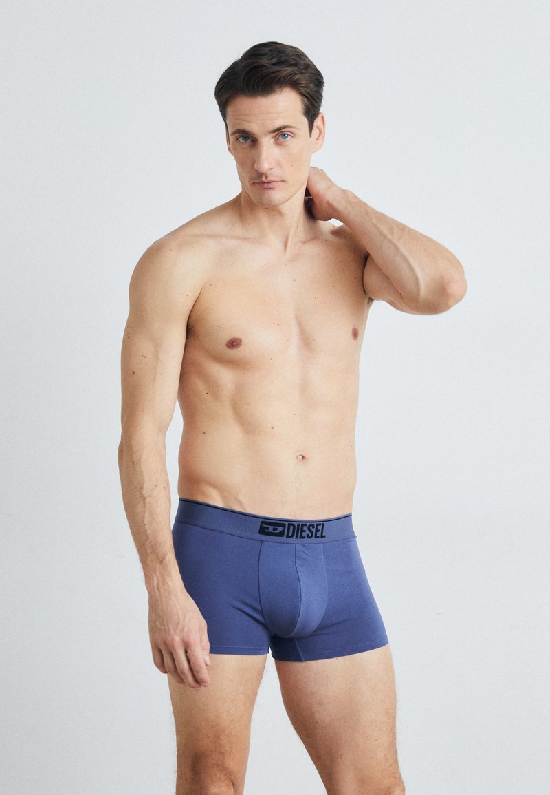 Navy blue Diesel boxer briefs with a black elastic waistband. The fabric appears smooth with minimal stitching and a contoured front design.