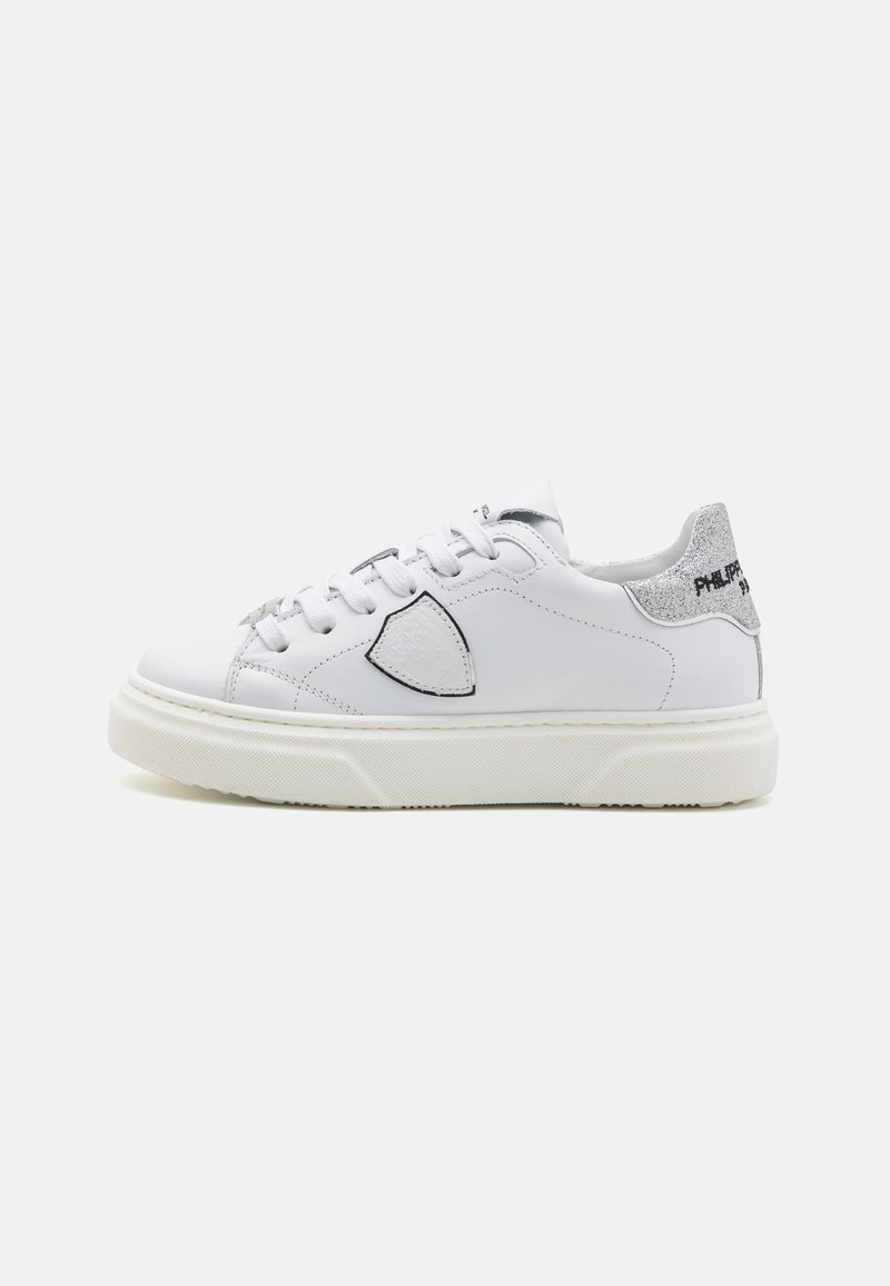 White leather sneakers with a textured silver heel and logo. Features a rounded toe, flat laces, and a thick rubber sole.
