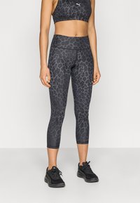 Μαύρα κολάν cropped με μοτίβο λεοπάρ, που διαθέτουν ψηλή μέση και ομαλή υφή. Συνδυάζονται με μαύρο αθλητικό σουτιέν και αθλητικά παπούτσια.