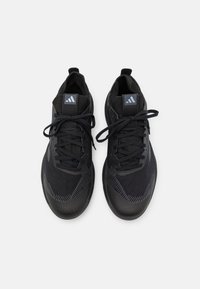 Czarne buty sportowe z teksturowaną cholewką, wyposażone w solidny czubek, okrągłe sznurowadła i logo na języku.
