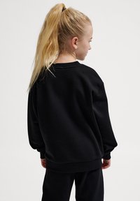 Svart sweatshirt i en avslappnad passform med rund halsringning och ribbad mudd. Tyget ser mjukt ut med en slät yta.