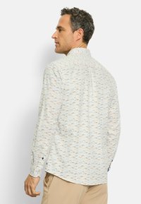 Weißes Langarmshirt mit einem mehrfarbigen Bergmuster in Rot und Blau. Mit knopfbaren Manschetten und einem kontrastierenden blauen Akzent.