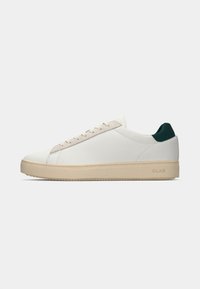 White leather sneaker with a beige sole, featuring a green heel accent and tonal laces. Smooth texture with minimal design details.