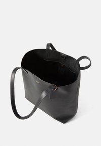 Geantă tote din piele neagră, cu două mânere, o deschidere superioară și un interior texturat. Include un buzunar lateral și un eticheta de marcă.