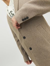Brauner Wollmantel mit maßgeschneidertem Design, ausgestattet mit einem Reverskragen, drei schwarzen Knöpfen und strukturiertem Stoff, schräg präsentiert.