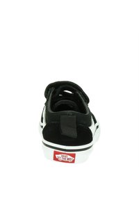 Zapatilla deportiva de ante negro con detalles blancos, una pestaña en el talón texturizada y un logo de Vans rojo en la suela. El diseño es de corte bajo con una forma clásica.