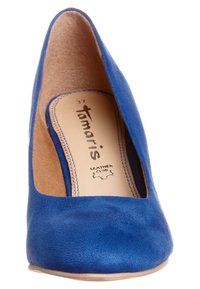 Blå mocka högklackad sko med rund tå, slät ytstruktur och läderinlägg som visar varumärket "Tamaris" och storlek 37.