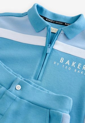Vaaleansininen poolopaita, jossa on vetoketjullinen kaulus, ribattu pinta, valkoiset raidat ja "BAKER BY TED BAKER" painettuna etuosaan; yhteensopivat siniset housut.