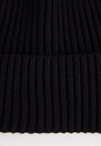 Mustav ribbikudoskangas paksulla tekstuurilla. Pystysuorat raidat luovat syvyyttä, korostaen materiaalin pehmeyttä ja lämpöä.