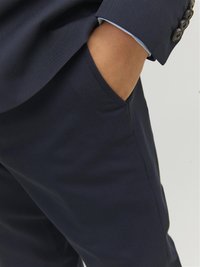 Pantaloni eleganti blu navy realizzati in tessuto morbido, con una tasca laterale e dettagli di cucitura in evidenza. Il risvolto presenta un'accenno blu chiaro.