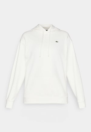Weißer Kapuzenpullover aus weichem Stoff, mit langen Ärmeln, einer Kordelzugkapuze und einem kleinen grünen Logo auf der Brust.