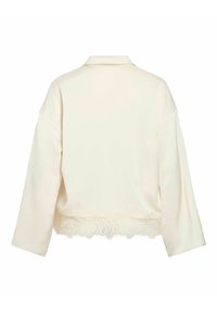 Elfenbenshvit bluse med krage, lange ermer og blonder i kanten nederst. Glatt stofftekstur, uformelt design, ingen synlige festemidler eller mønstre.