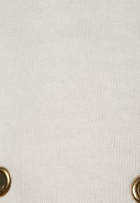 Wit geribd stof met twee gouden ringen. De textuur is glad met een subtiel, gelijkmatig patroon. Het ontwerp is eenvoudig en minimalistisch.