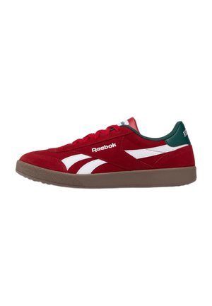 Sneaker rossa Reebok con strisce del logo bianche, colletto del tallone verde scuro, suola marrone e lacci rossi mostrata di profilo laterale.