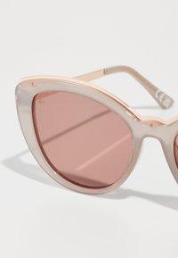 Óculos de sol estilo gato com armações transparentes e rosa, lentes cor-de-rosa e detalhes metálicos nas hastes. Textura suave e design ousado.
