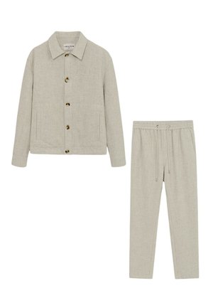 Ensemble deux pièces beige avec une veste boutonnée comportant des poches avant et un pantalon assorti à cordon de serrage.