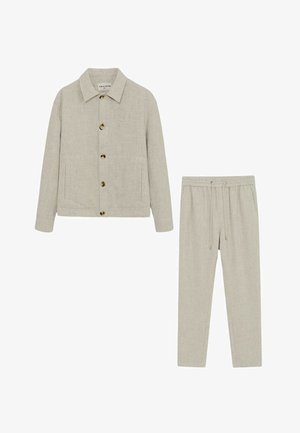 Ensemble deux pièces beige avec une veste boutonnée comportant des poches avant et un pantalon assorti à cordon de serrage.