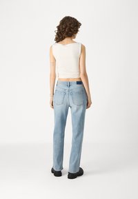 Jeanși din denim ușor, cu talie înaltă, de culoare albastră, cu un croi tapered, având două buzunare la spate și o petică contrastantă la talie.