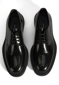 Chaussures en cuir verni noir avec une surface lisse, un design à lacets et un bout rond. Semelle texturée avec un léger bord strié pour une meilleure adhérence.