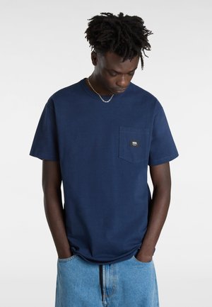 Camiseta de algodón azul marino con cuello redondo, mangas cortas y un bolsillo en el pecho izquierdo que presenta una pequeña etiqueta con el logo. Corte recto.
