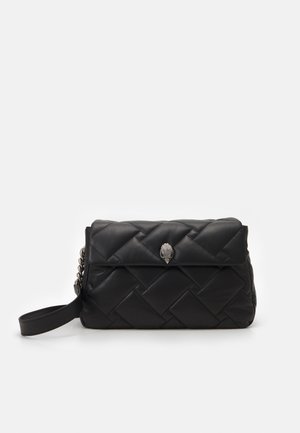 Pochette en cuir matelassé noir avec fermeture en forme de tête de serpent en argent et petite lanière de poignet, sur fond blanc uni.