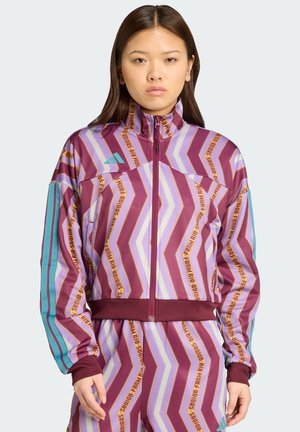 Lilla og lavendel zigzag-mönstrad jacka med hög krage, zip upp framtill och teal detaljer på ärmarna. Ribbad mudd och midja.