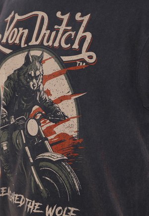 Camiseta gráfica negra con un jinete lobo montando una motocicleta, con detalles desgastados en rojo y blanco y el texto "Von Dutch" arriba.