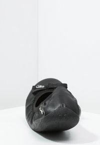 Svart ballerina med mjukt läderöverdrag, elastiskt band och strukturerad gummisula. Har rund tå och minimalistisk design.