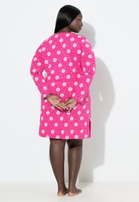 Vestido rosa con estampado floral, de manga larga y cuello redondo, con una forma ligeramente acampanada y aberturas laterales en el dobladillo.