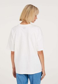 Weißes Baumwoll-T-Shirt mit lockerer Passform, kurzen Ärmeln und rundem Halsausschnitt. Verfügt über ein kleines Logo auf dem oberen Rücken.