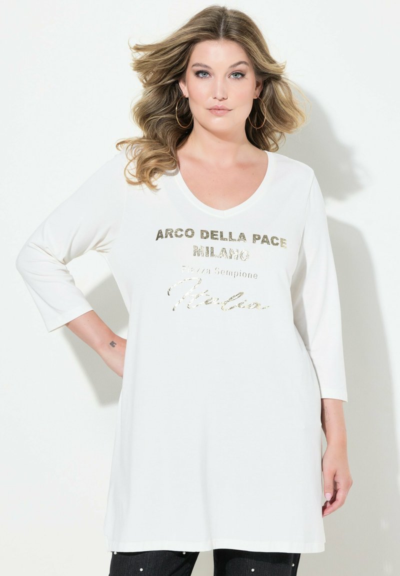 Weiße Langarm-Tunika mit weitem Ausschnitt und metallisch goldener Schriftzug "ARCO DELLA PACE MILANO" auf der Brust.