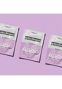 Pakete der "Peptide Straffend & Glättend Maske" mit rosa-weißem Design, versehen mit Symbolen und Texten, die Vorteile und Inhaltsstoffe auf einem violetten Hintergrund erläutern.