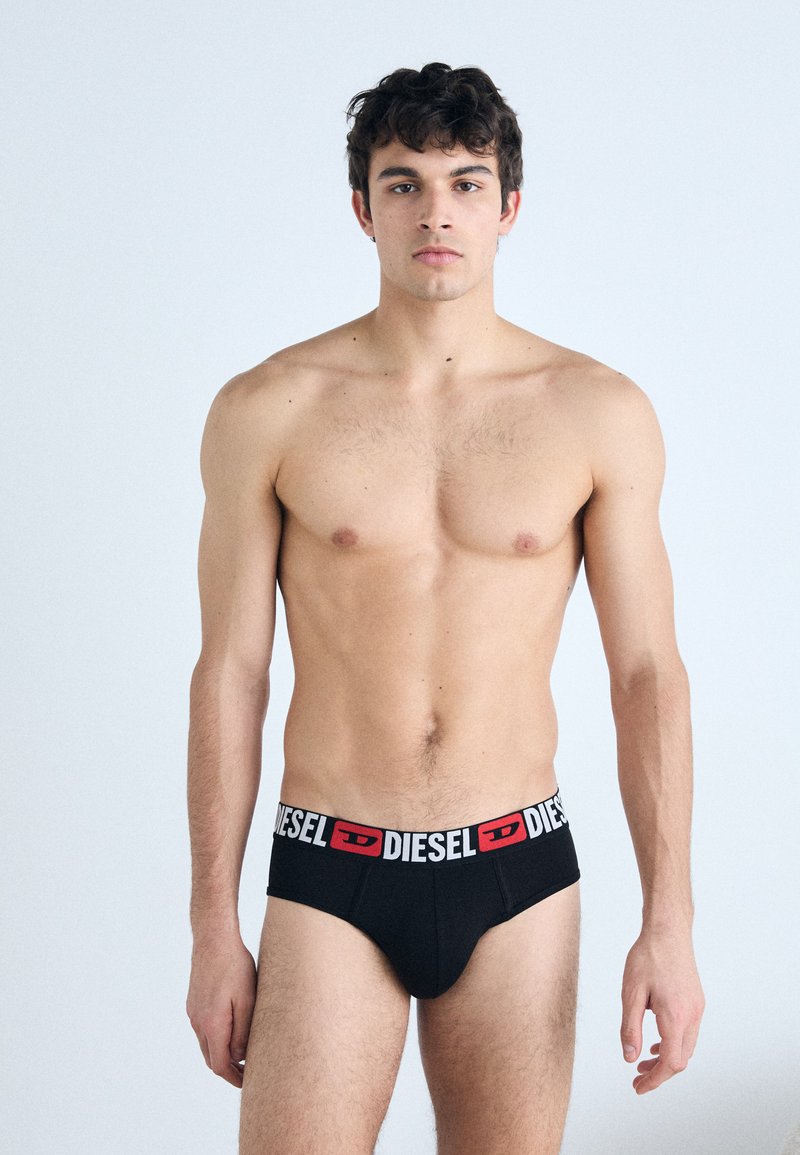 Culotte noire de style boxer avec une ceinture de marque blanche et rouge, fabriquée dans un tissu lisse, ajustement serré et design minimaliste.