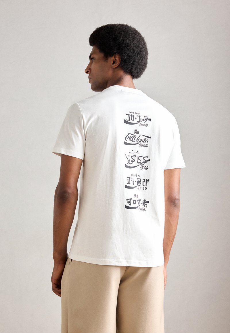Witte katoenen t-shirt met grafische tekst op de achterkant in verschillende talen, met een ronde halslijn en korte mouwen.