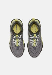 Graue Outdoor-Schuhe mit strukturiertem Finish, ausgestattet mit gelben Akzenten, perforiertem Obermaterial, zweifarbigen Schnürsenkeln und einer robusten Sohle für besseren Halt.