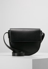 Borsa a tracolla in pelle nera con forma arrotondata, pattina pieghevole e cuciture bianche a contrasto. Spallaccio regolabile per comodità.