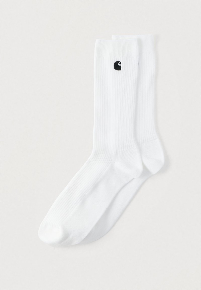 Λευκές κάλτσες πλήρους μήκους με ρβιδωτή υφή, που διαθέτουν ένα μικρό μαύρο λογότυπο στο πλάι. Το ύφασμα φαίνεται απαλό και ελαστικό.